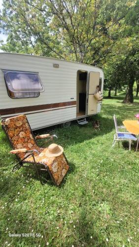 an rv parked in the grass with a table and chairs at CHEZ JOSETTE caravane Camping le sorbier Montignac Lascaux in Montignac