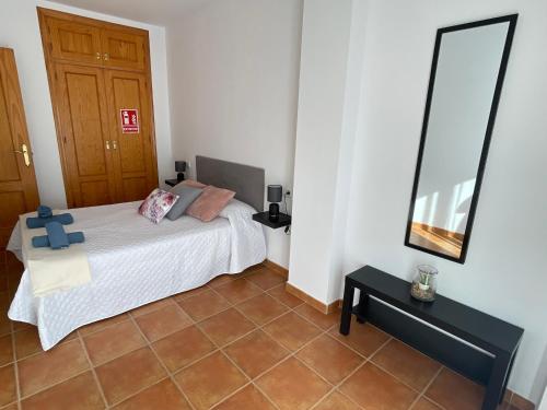 a bedroom with a white bed and a mirror at Apartamento de Frigiliana ,2 in Frigiliana