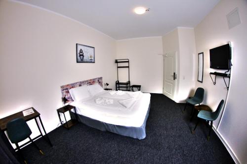 a bedroom with a bed and a tv and chairs at Hotel Karlshorst in Berlin
