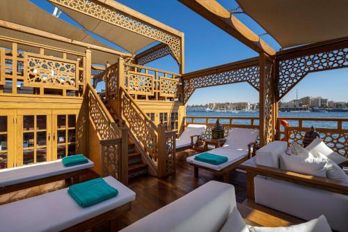 a balcony with white chairs and a view of the water at EL Hanim Dahabeeyah in Luxor
