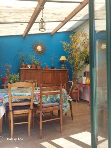 une salle à manger avec une table, des chaises et un mur bleu dans l'établissement Maison rustique à la campagne, à Monthou-sur-Cher