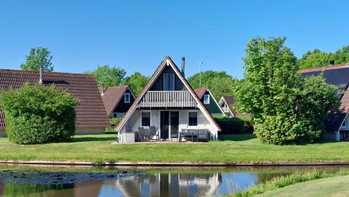 a house with a thatched roof next to a lake at Gramsbergs Huuske in Gramsbergen