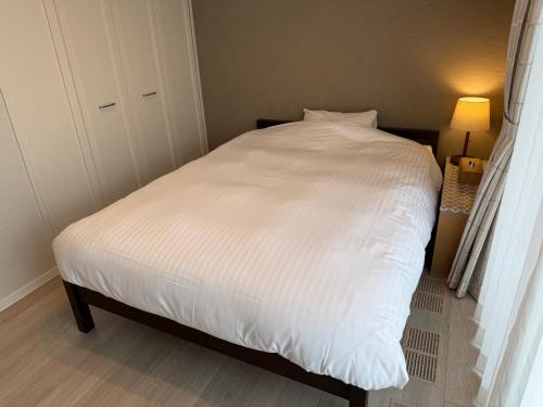 a bed in a bedroom with a white comforter at Pets OK Stunning view of Mt Fuji Near Kawaguchiko Beautiful new facilities ASTLAND in Fujikawaguchiko
