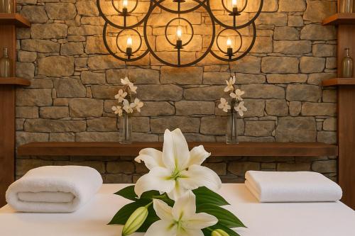 a bathroom with towels and flowers on a table at Regnum Banya Thermal Hotel in Banya