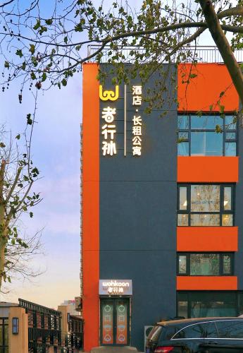 Un edificio con un cartel en el costado. en Wohkoon者行孙青年酒店北京南站草桥店, en Beijing