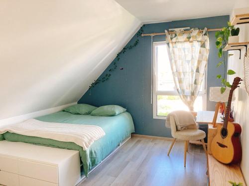a bedroom with a bed and a guitar at KER NALA - Jolie maison familiale pour 5 vacanciers in Plouharnel