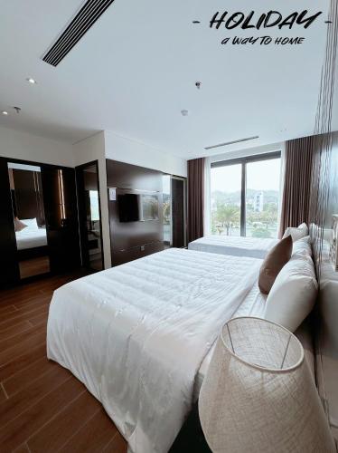 a bedroom with a large white bed with a large window at Holiday Hotel Van Don in Tài Xá
