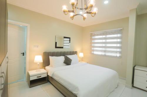 a bedroom with a white bed and a chandelier at Accra Luxury Apartments @ Silicon Square in Accra