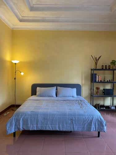a bedroom with a blue bed with a yellow wall at 'Nanini Backyard' Home Stay in Berastagi