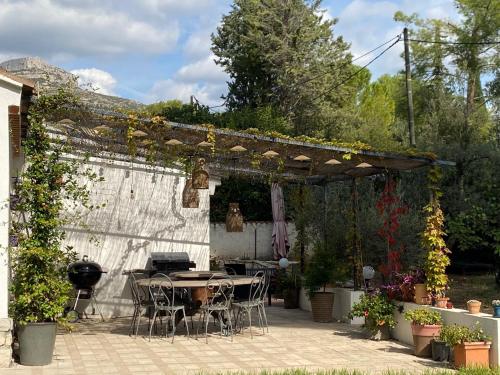 un patio avec une table et des chaises sous une pergola dans l'établissement Le Mas du Garlaban, à Aubagne