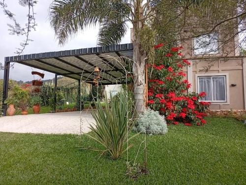 een pergola voor een huis met rode bloemen bij El parque in Vaqueros