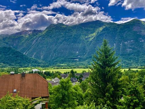a view of a mountain range with a house and a tree at Apartma Lina in Bovec