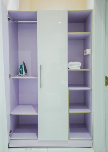 a closet with purple walls and white shelves at Accra Luxury Apartments @ Silicon Square in Accra