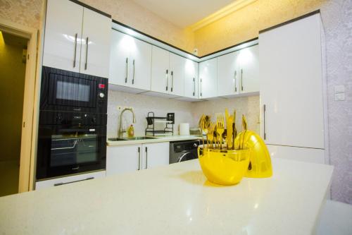 a kitchen with white cabinets and a yellow bowl filled with knives at Accra Luxury Apartments @ Silicon Square in Accra