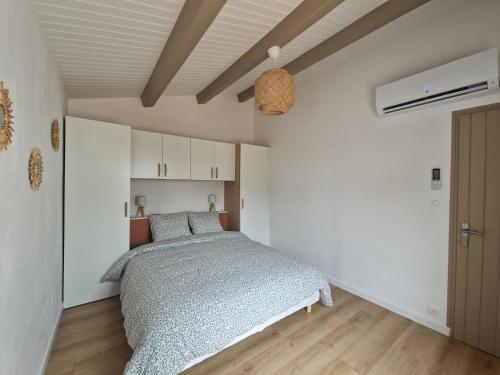 une chambre avec un lit et un mur blanc dans l'établissement Maison familiale à Barbâtre face à la dune, 3 chb, 2 SDB, 8 personnes, à Barbâtre