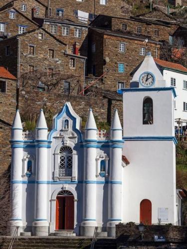 a small white church with a clock on it at Encanto de Xisto in Piódão