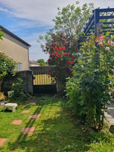 a garden with a gate and a bush with red flowers at La maison de Sophie in Carresse