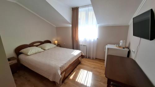 a bedroom with a bed and a flat screen tv at Затишні апартаменти в центрі Трускавця in Truskavets