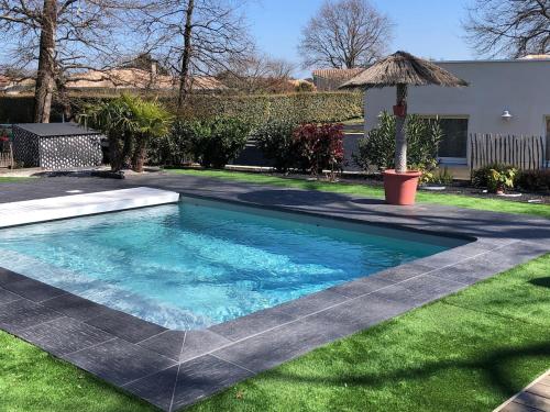 een zwembad in een tuin met een parasol bij La Casa d'Audenge in Audenge