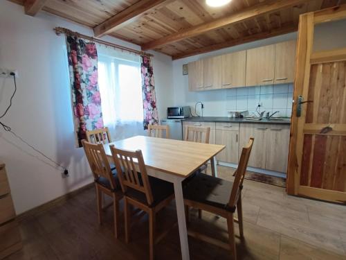 a kitchen with a wooden table and chairs at Przy wodzie - Jacnia in Jacnia