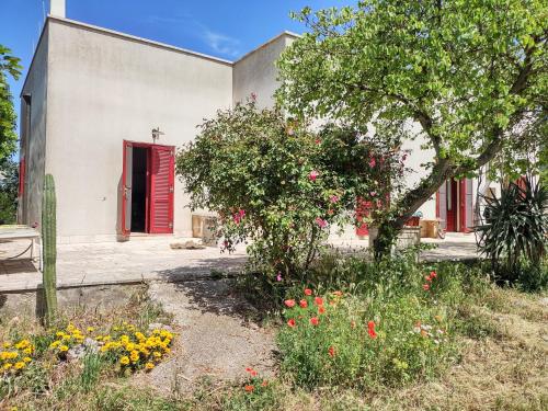 a building with a red door and a garden with flowers at La Specchia - Dimore in natura in Cisternino