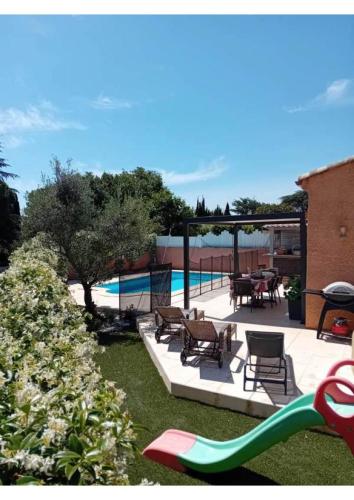 d'une terrasse avec des chaises, des tables et un toboggan. dans l'établissement Charmante villa tout confort,sans vis a vis avec piscine, à Maraussan