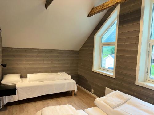 a bedroom with two beds and two windows at Brekke Gard Hostel in Flåm