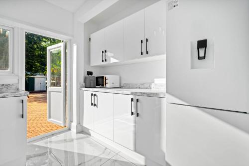 a white kitchen with white cabinets and a window at NEC BHX Free Parking Luxury Prestige Cosy Elegance in Birmingham