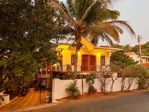 a yellow house with a palm tree in front of it at Peaceful Studios in Assagao in Parra