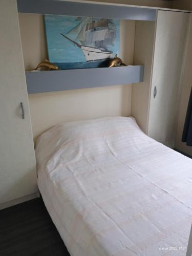 a small bedroom with a white bed in it at CHALET Les ALGUES in Plobannalec-Lesconil