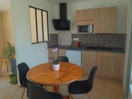 une petite cuisine avec une table et des chaises en bois dans l'établissement Gîte du Roc 1, à Les Portes du Coglais