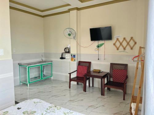 a room with two chairs and a table and a tv at T'H Homestay in Mui Ne