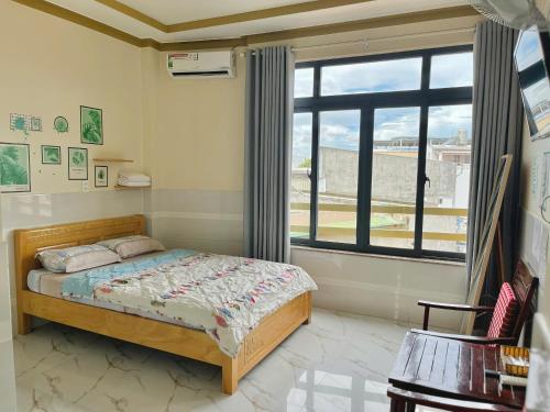 a bedroom with a bed and a large window at T'H Homestay in Mui Ne