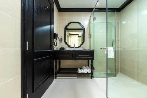 Thôn Mỹ PhướcにあるGrand Luxury Hotel Phan Rangのガラスのシャワーと洗面台を備えたバスルーム