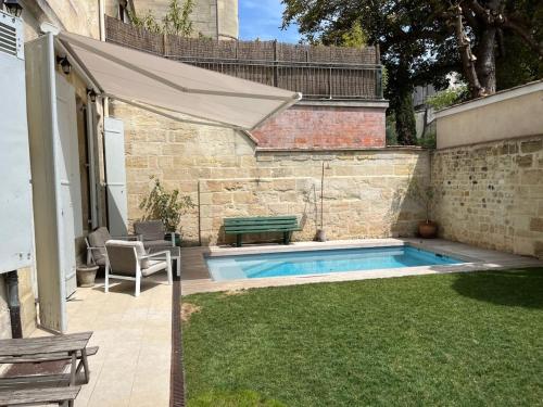 - une piscine dans une cour avec un banc et un parasol dans l'établissement Maison en centre ville avec jardin et piscine, à Bordeaux