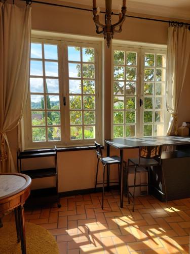 une pièce avec une table, des chaises et des fenêtres dans l'établissement Rue du Château, à Lalinde