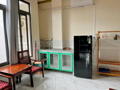 a kitchen with a black refrigerator and a table at T'H Homestay in Mui Ne