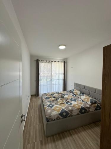 a bedroom with a bed and a window at Niko Apartaments Shengjin in Shëngjin