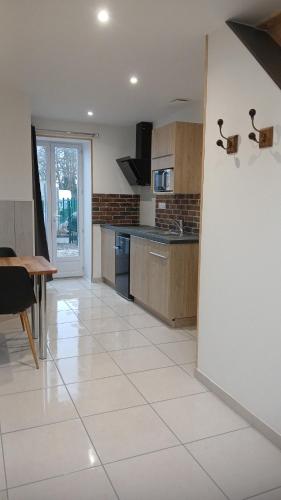 Il comprend une cuisine avec du carrelage blanc et une table. dans l'établissement Gîte du Roc 2, à Les Portes du Coglais