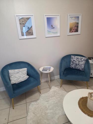 two blue chairs and a table in a living room at Spring Tide Beach Flat Child Petfriendly Hot Tub in Bloubergstrand