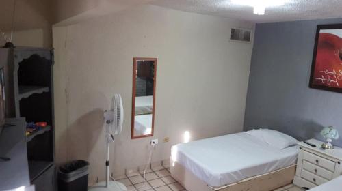 Un dormitorio con una cama blanca y un espejo. en Torreón 2 - Habitación cerca del aeropuerto con alberca, en Torreón