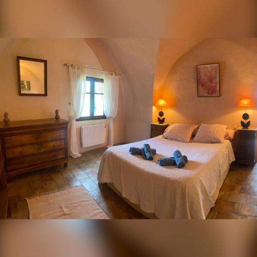 - une chambre dotée d'un lit avec deux chaussures bleues dans l'établissement Bastide de Bénezet, à Mérindol