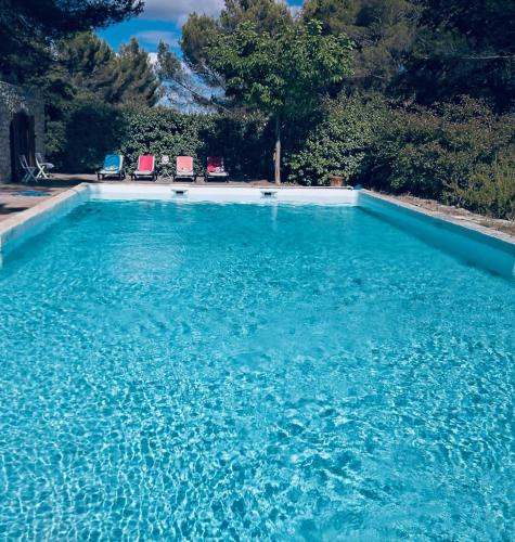 une grande piscine d'eau bleue avec 2 chaises dans l'établissement Bastide de Bénezet, à Mérindol