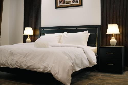 a bedroom with a large white bed with two lamps at LMY Stays Bahria Prestige Apartments Lahore in Lahore