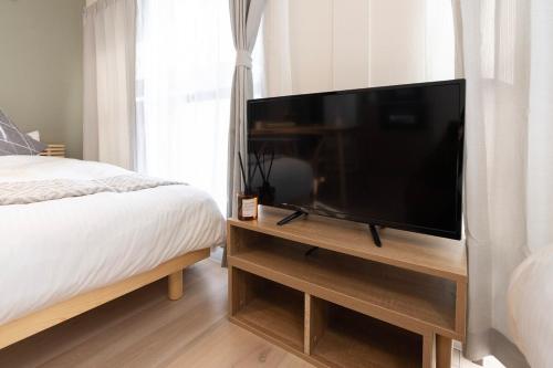 a bedroom with a large flat screen television on a wooden stand at Alpha memory NAGOYA in Mutsunochō