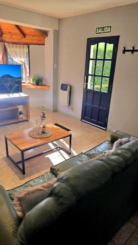a living room with a couch and a table and a door at Rincon de la Araucaria Dina Huapi in Dina Huapi