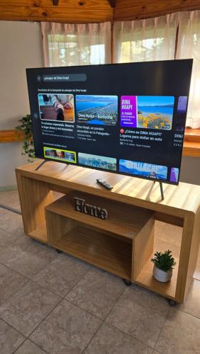 a large flat screen tv sitting on a wooden stand at Rincon de la Araucaria Dina Huapi in Dina Huapi