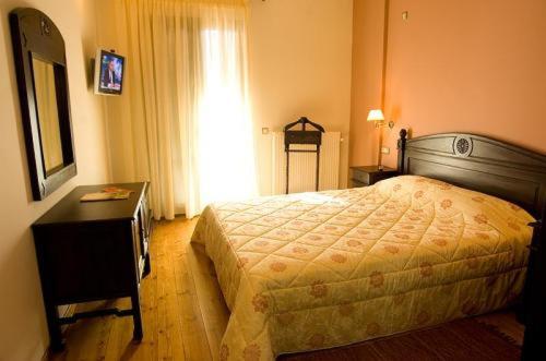 a bedroom with a bed and a dresser and a mirror at Vytina Mountain View Hotel in Vytina