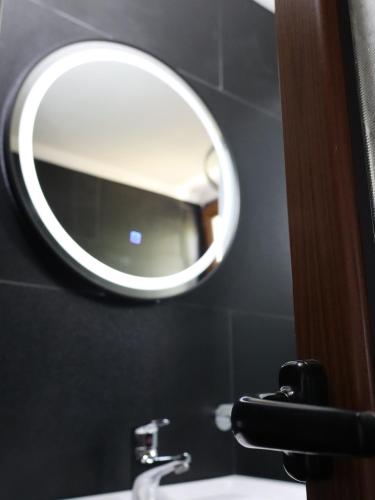 a mirror on a wall above a bathroom sink at Bujtina ANLU in Gjirokastër