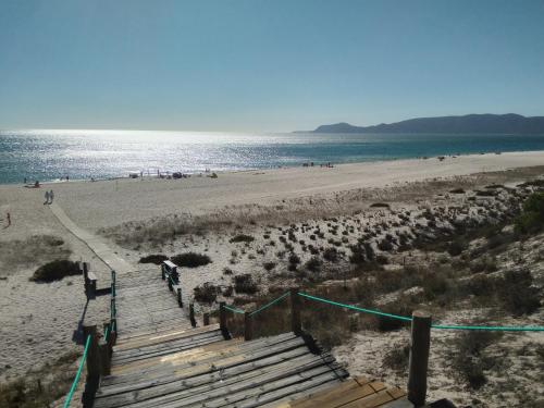 a wooden staircase leading to a beach with people on it at Troia Beach Villa in Troia